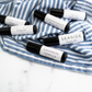 Variety of amber glass roller bottle perfume oils laying on a blue and white striped kitchen towel.